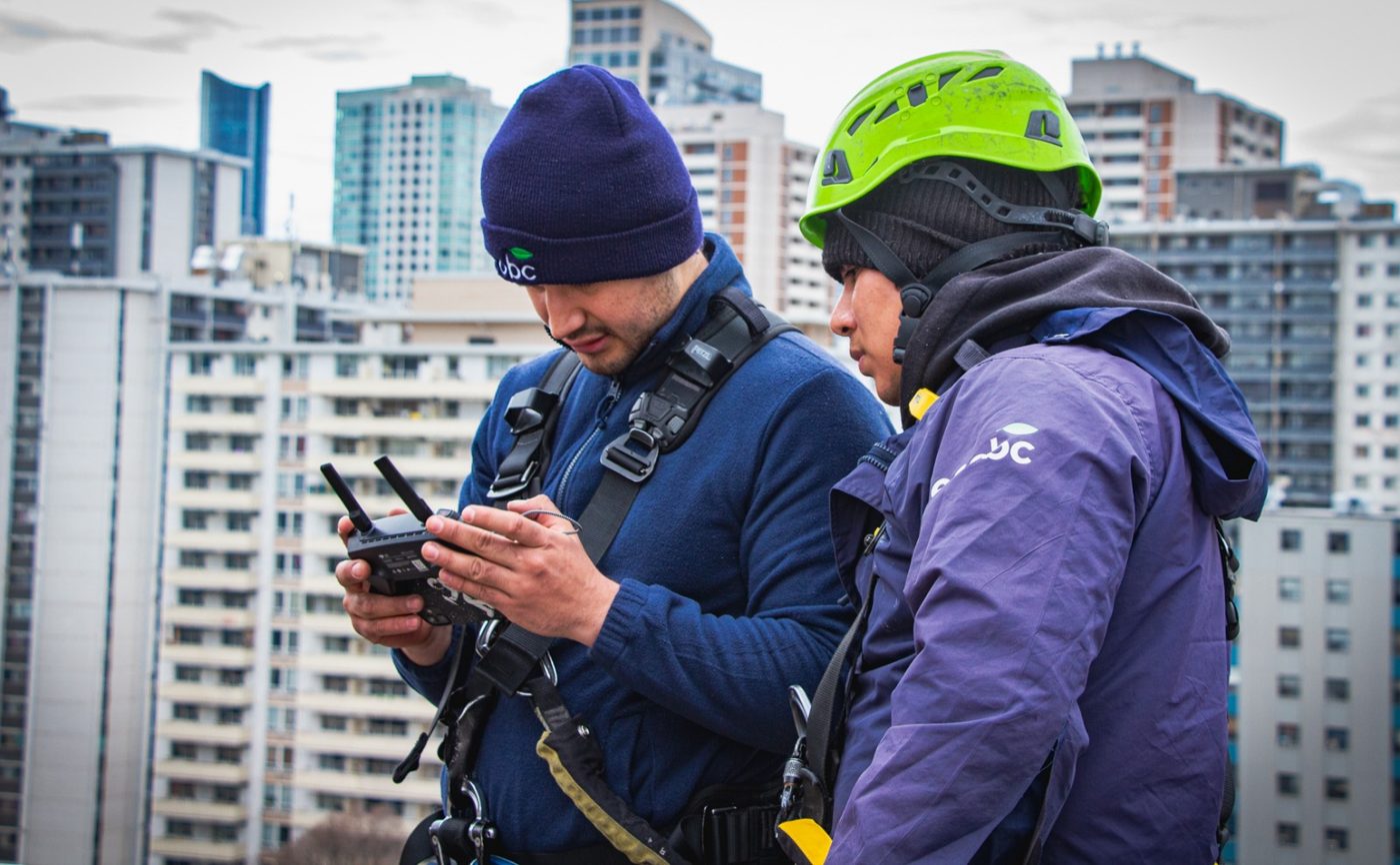 ecobc crew documenting rooftop work with the Toronto skyline behind
